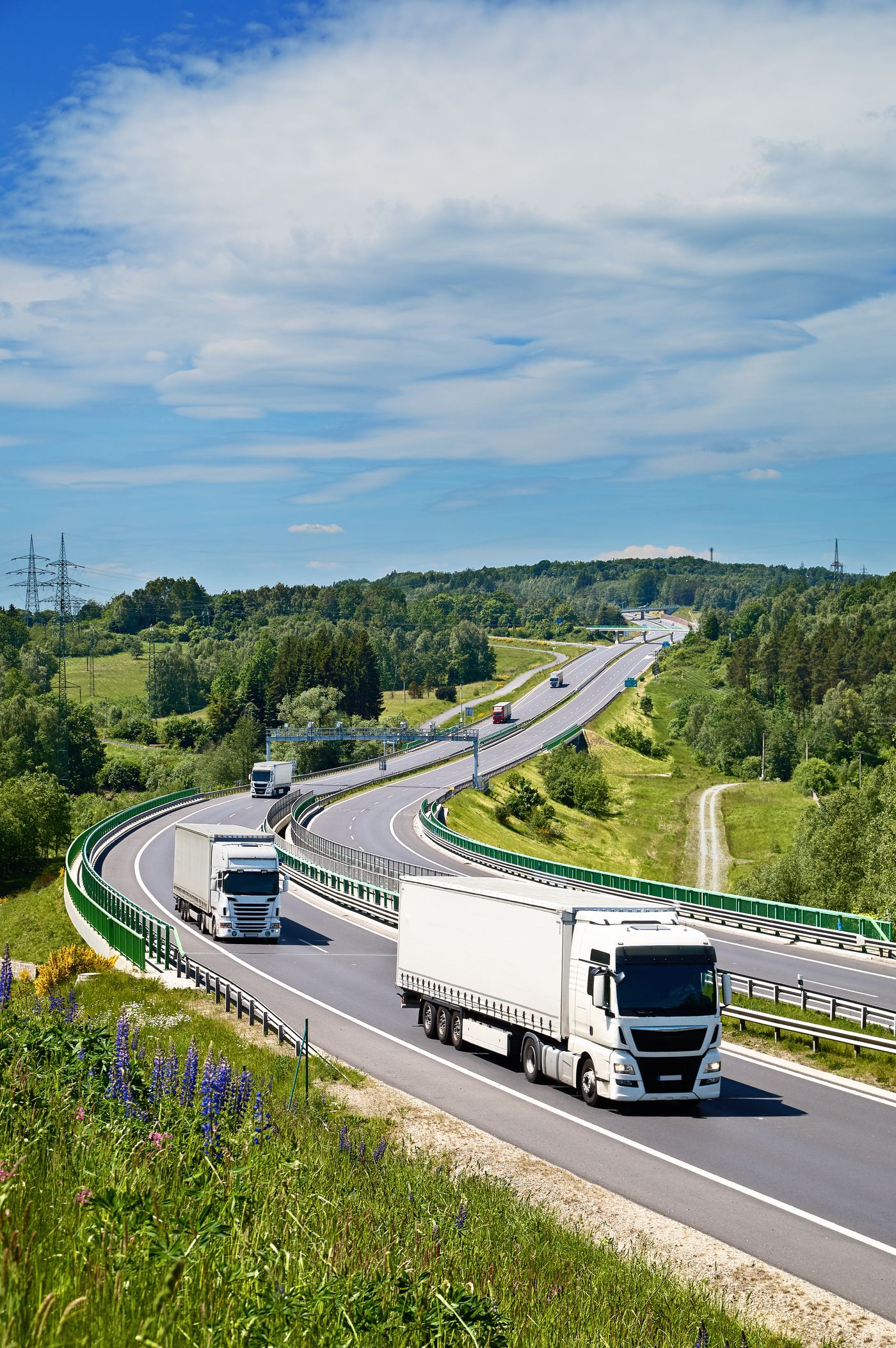 Freight trucks traveling on a divided highway through green countryside